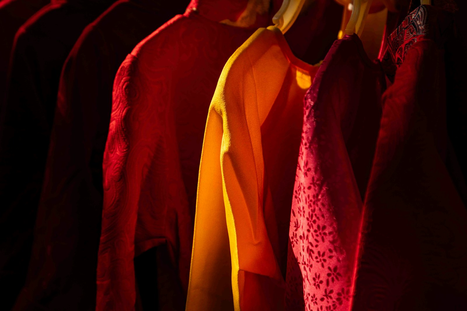 Row of colorful clothes hanging in a closet.