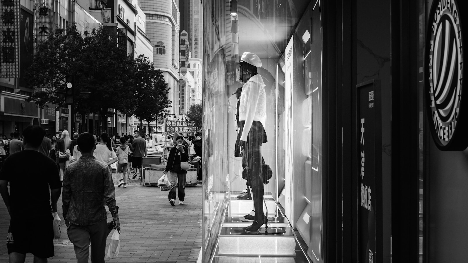 A black and white photo of people walking down a sidewalk